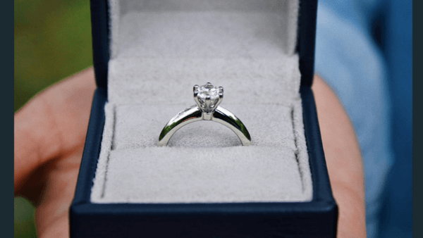 Hand holding engagement ring in a box